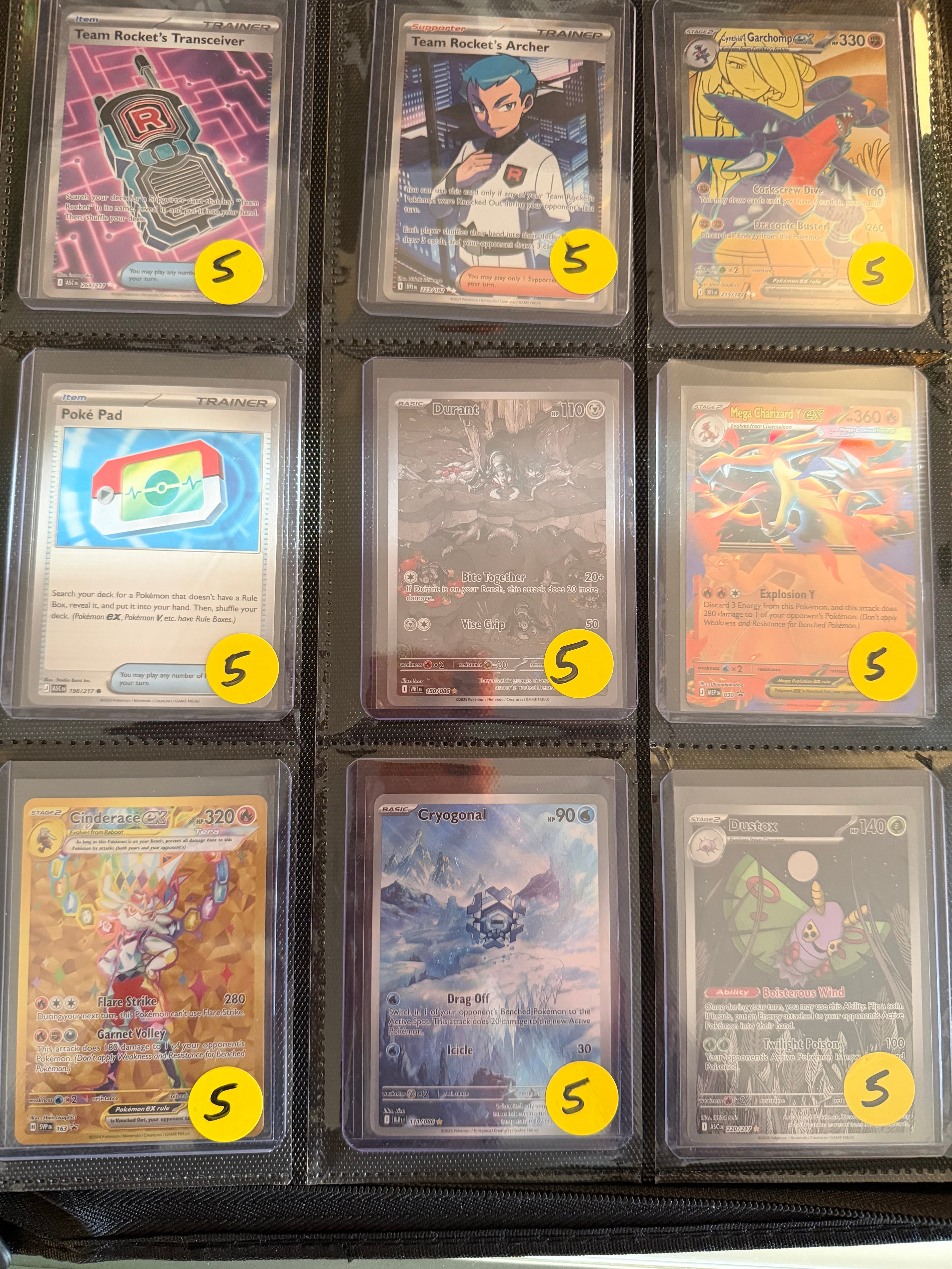Nine Pokémon trading cards in a binder, each with a yellow sticker marked five.